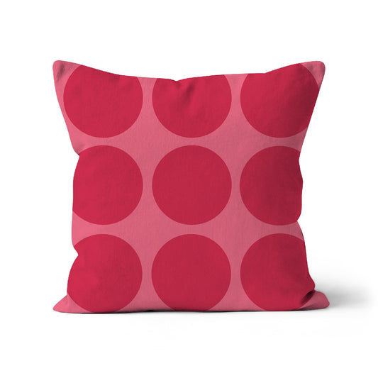 Square shaped cushion with large dark pink spots on a light pink background.