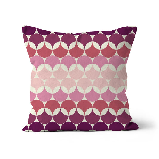 Square shaped cushion with Bauhaus style pattern, interlinking circles in purples + shades of pink colour combination against a cream background.