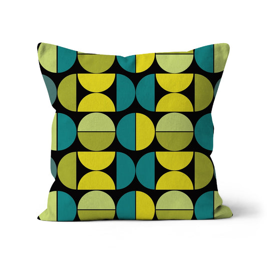 Square shaped cushion with Bauhaus style graphic pattern of repeating graphic circles and half circles in pale greens, yellow and teal green with a black background.