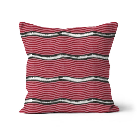 Cushion with a pattern of red and pink stripes and graphic stripe of white dimond shapes on a black.